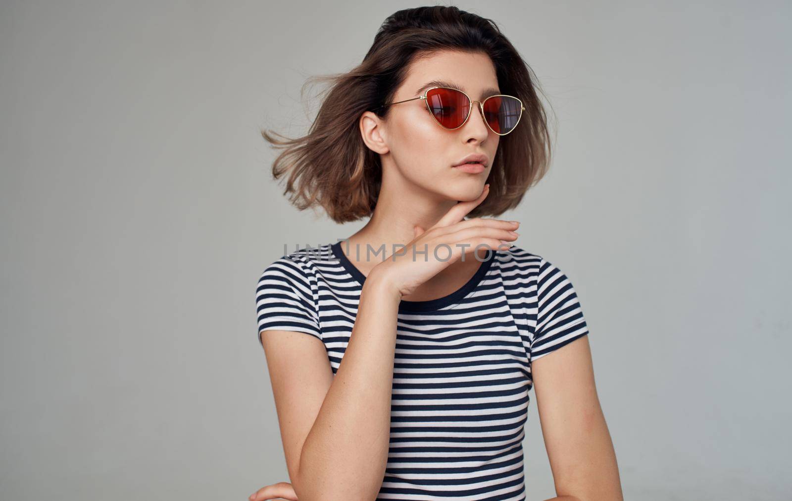 romantic woman in striped t-shirt portrait on gray background and fashionable glasses on face. High quality photo