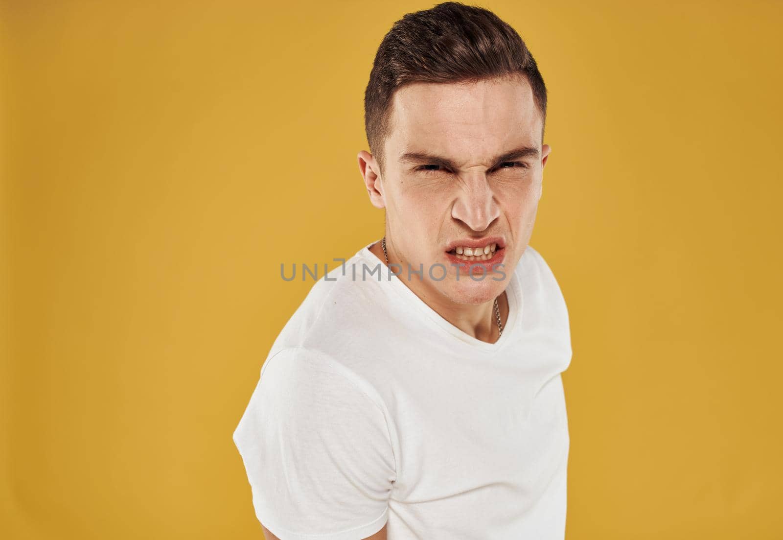 Side view of a man in a white T-shirt on a yellow background. High quality photo