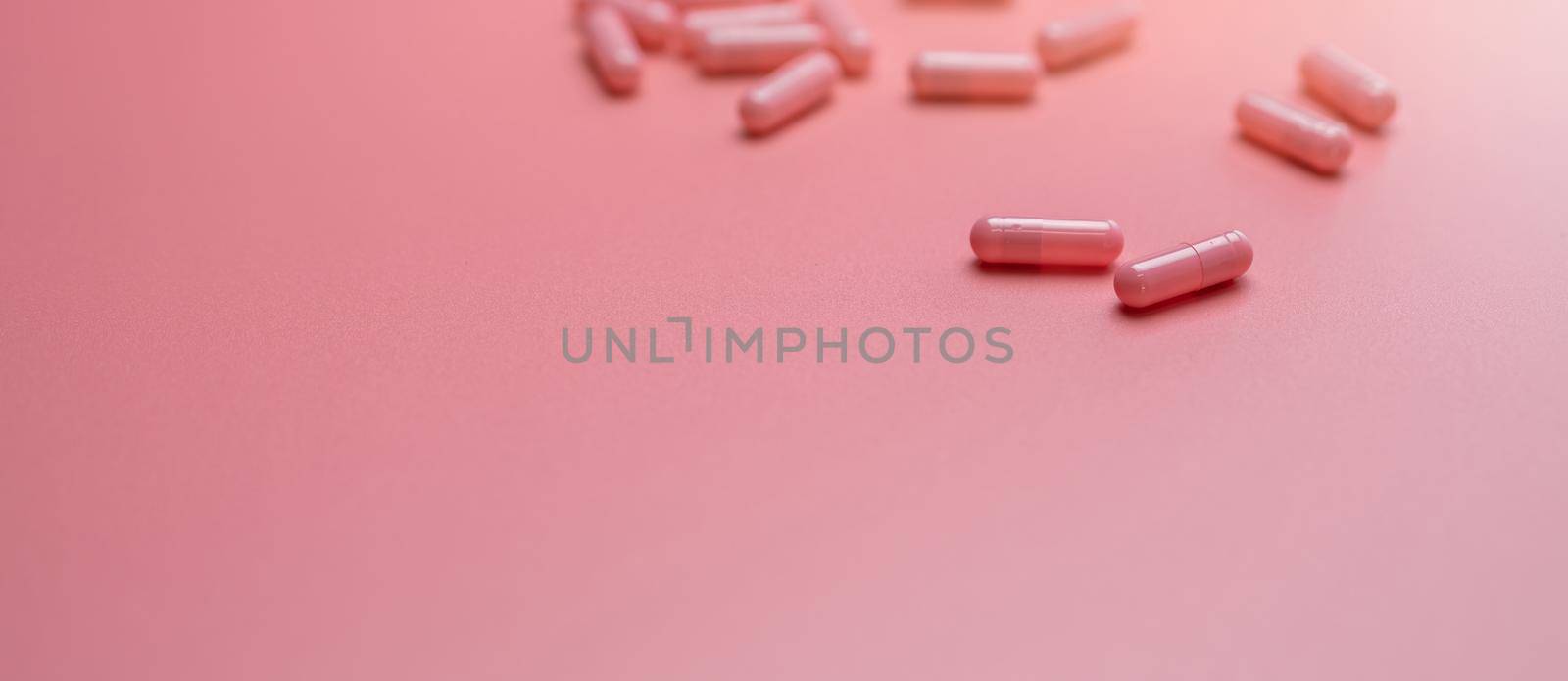 Pink capsules pill spread on pink background. Vitamins and supplements for healthy skin, collagen boost, and acne treatment concept. Online pharmacy. Pharmacy store banner. Pharmaceutical industry.