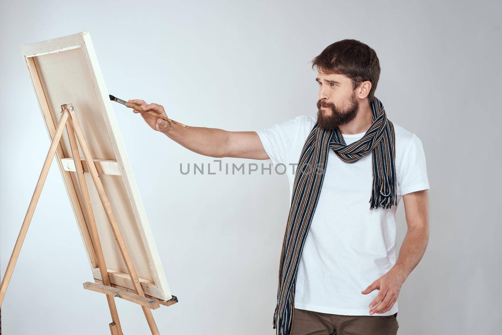 male artist painting on easel art lifestyle light background. High quality photo