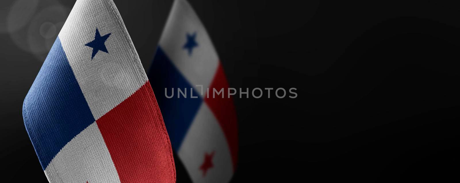 Small national flags of the Panama on a dark background.