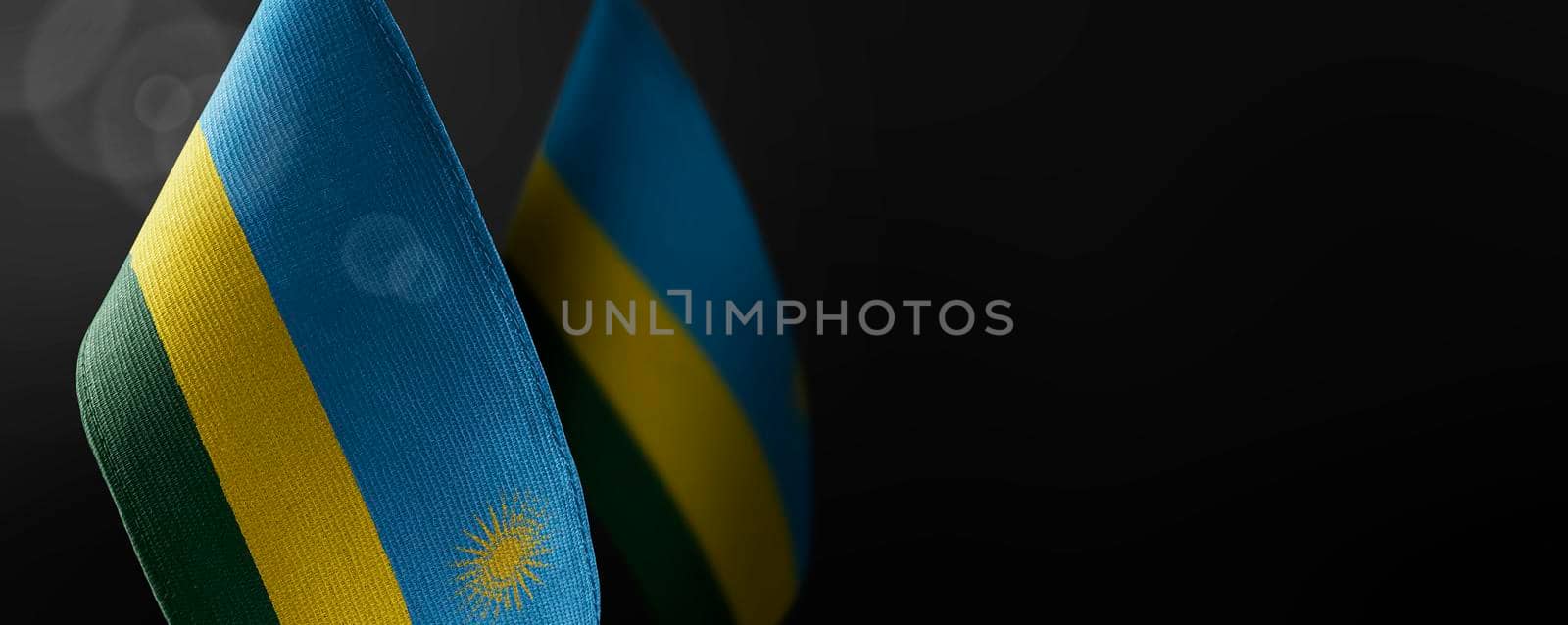 Small national flags of the Rwanda on a dark background.