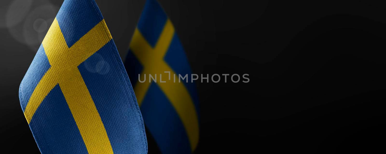 Small national flags of the Sweden on a dark background.