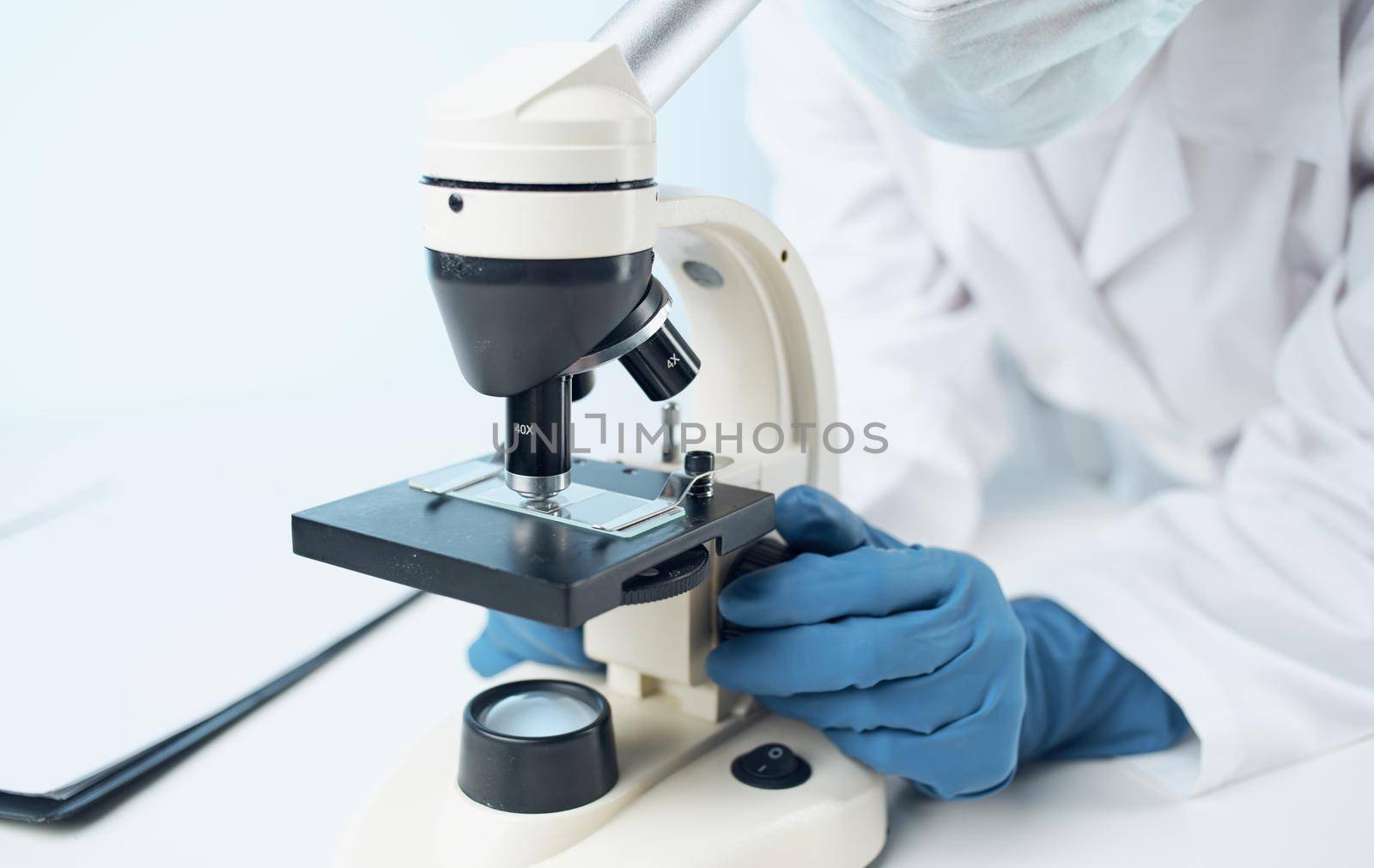 woman in a medical gown in blue gloves stands near the flask and biology chemical element vaccination. High quality photo