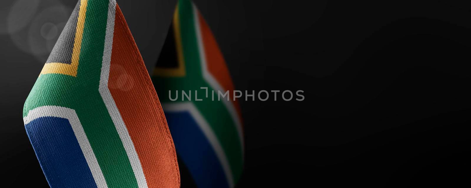 Small national flags of the South Africa on a dark background.