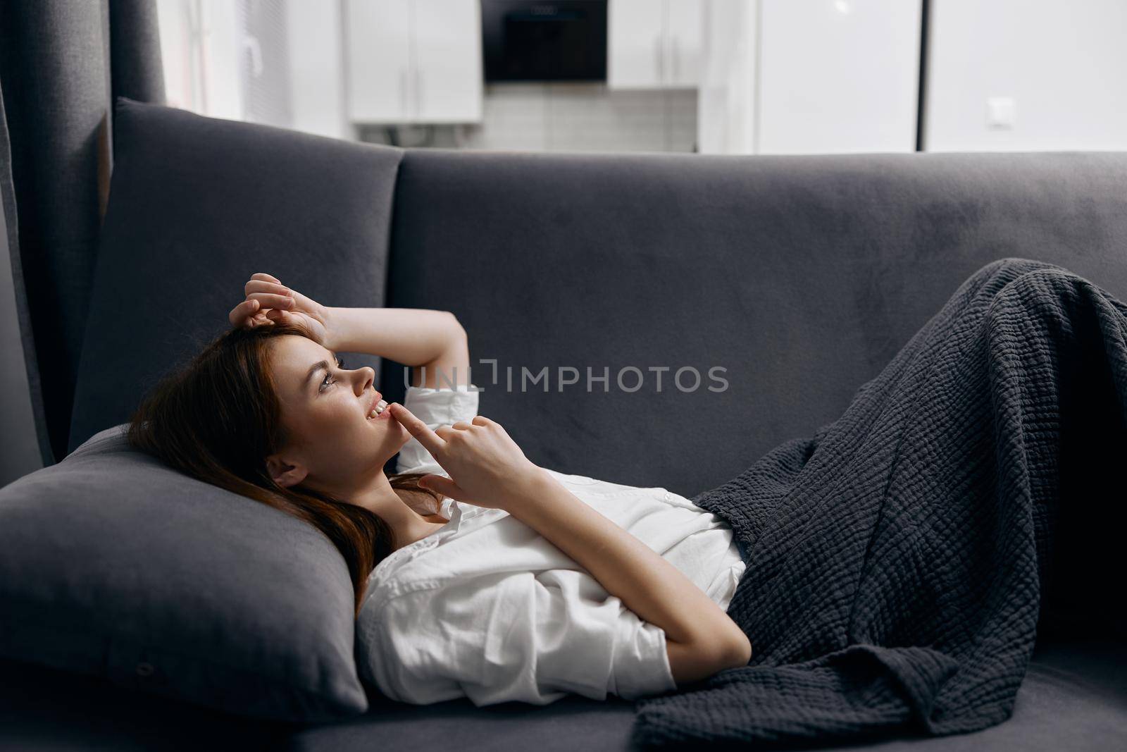 red-haired woman lying on the sofa and gesturing with her hands side view. High quality photo