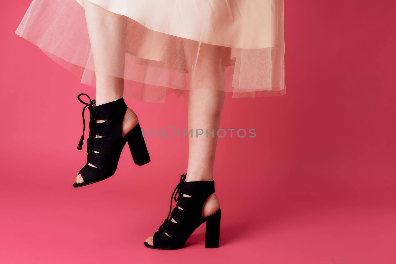 Female feet black fashionable heels shoes charm pink background by SHOTPRIME