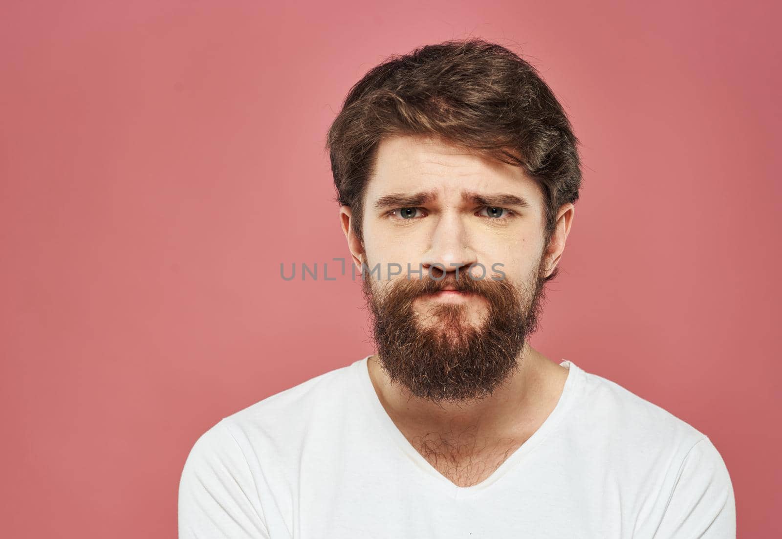 Man on a pink background portrait white t-shirt bushy beard. High quality photo