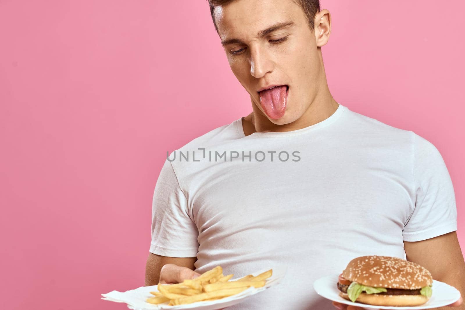 man in white t-shirt hamburger lifestyle pink background eating. High quality photo