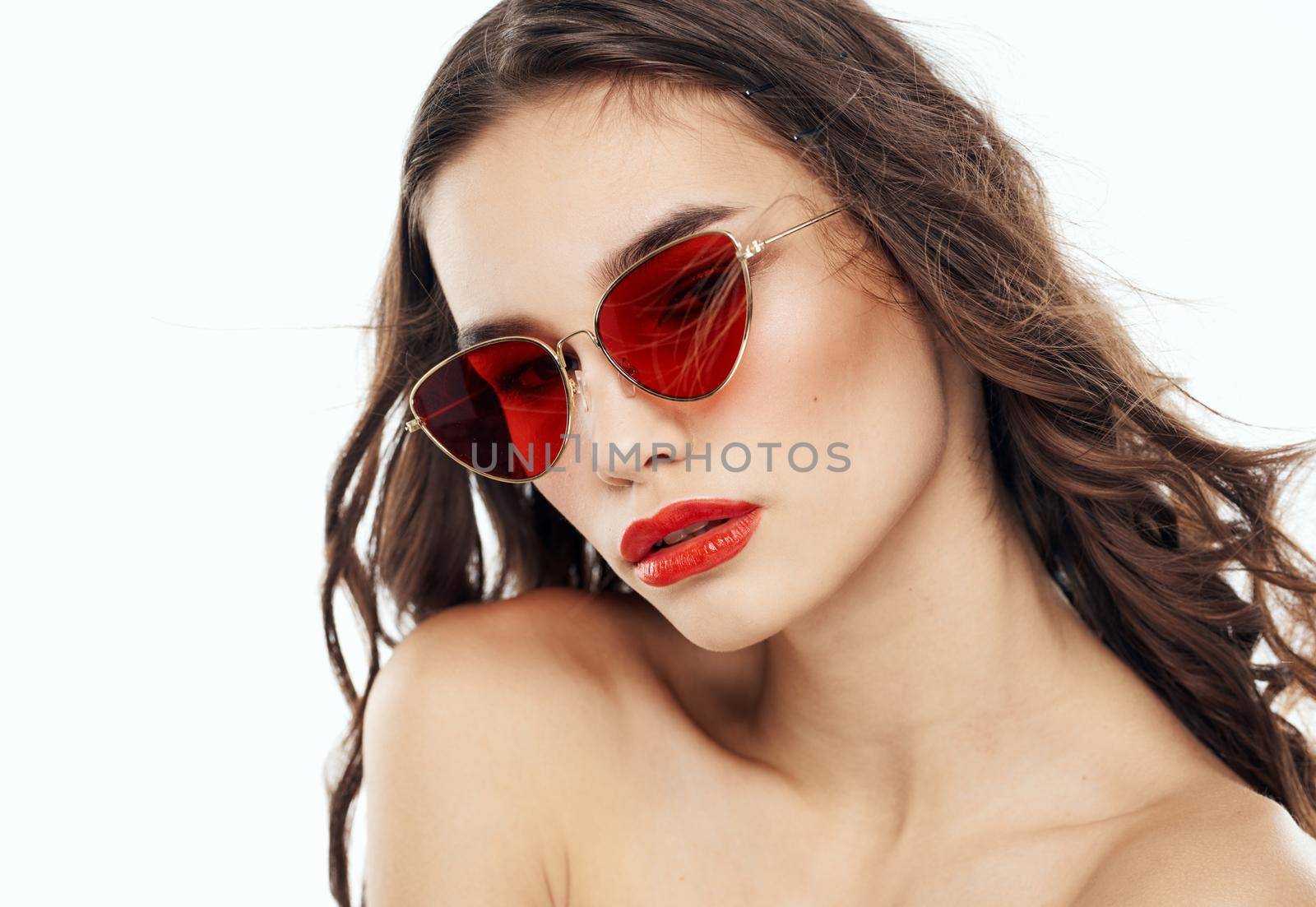 Portrait of a beautiful woman with bared shoulders and in sunglasses on a light background. High quality photo
