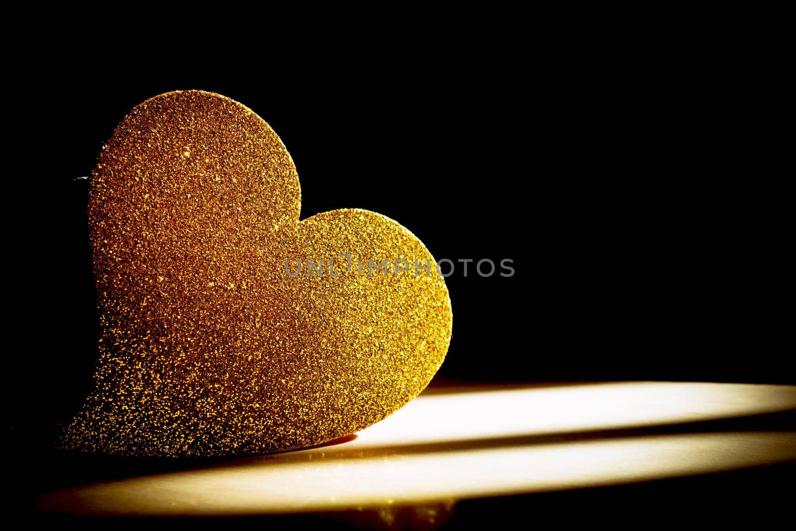 Golden shiny heart on black background