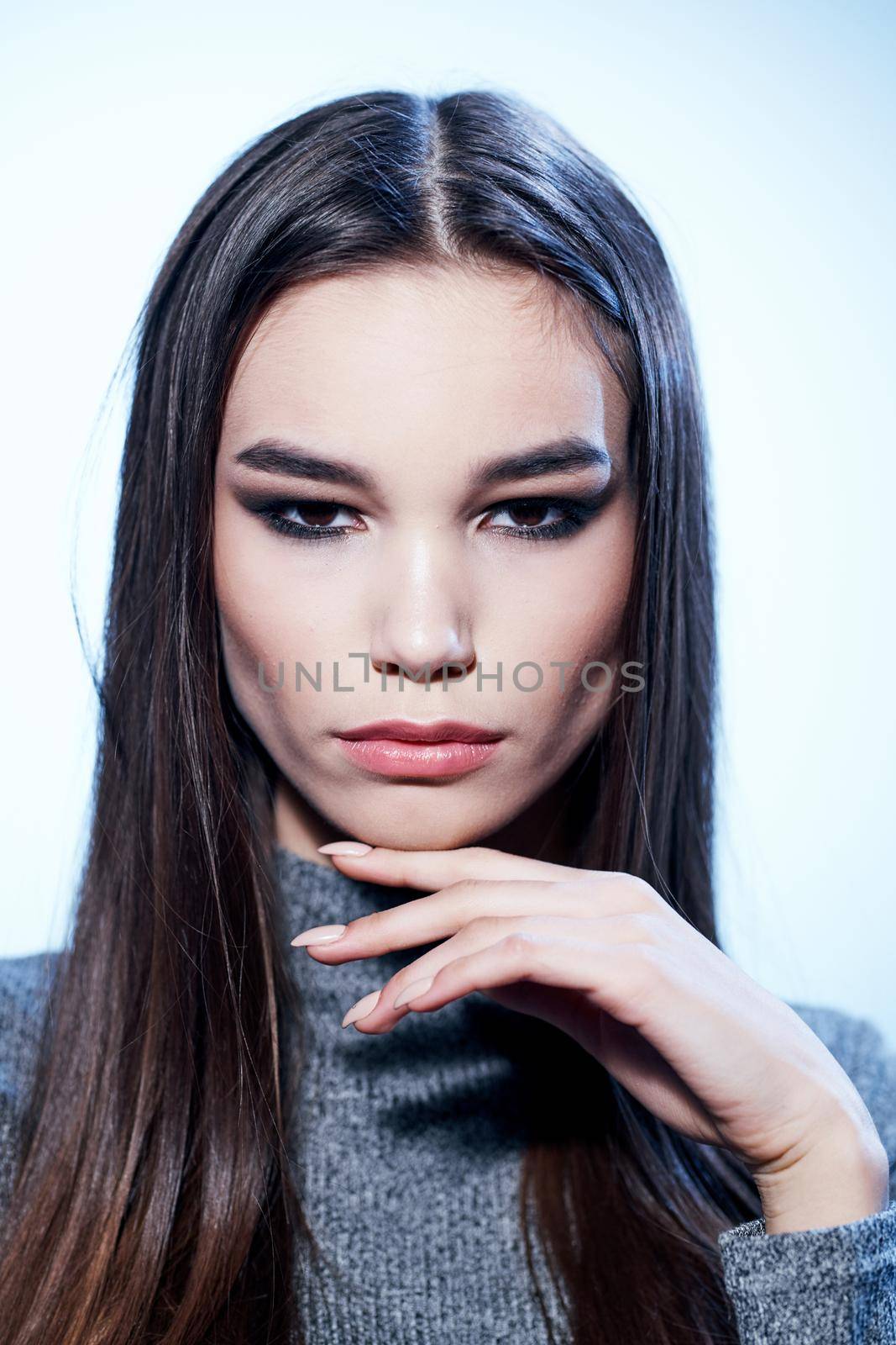 Beautiful brunette model in gray sweater with makeup cropped view on light background. High quality photo