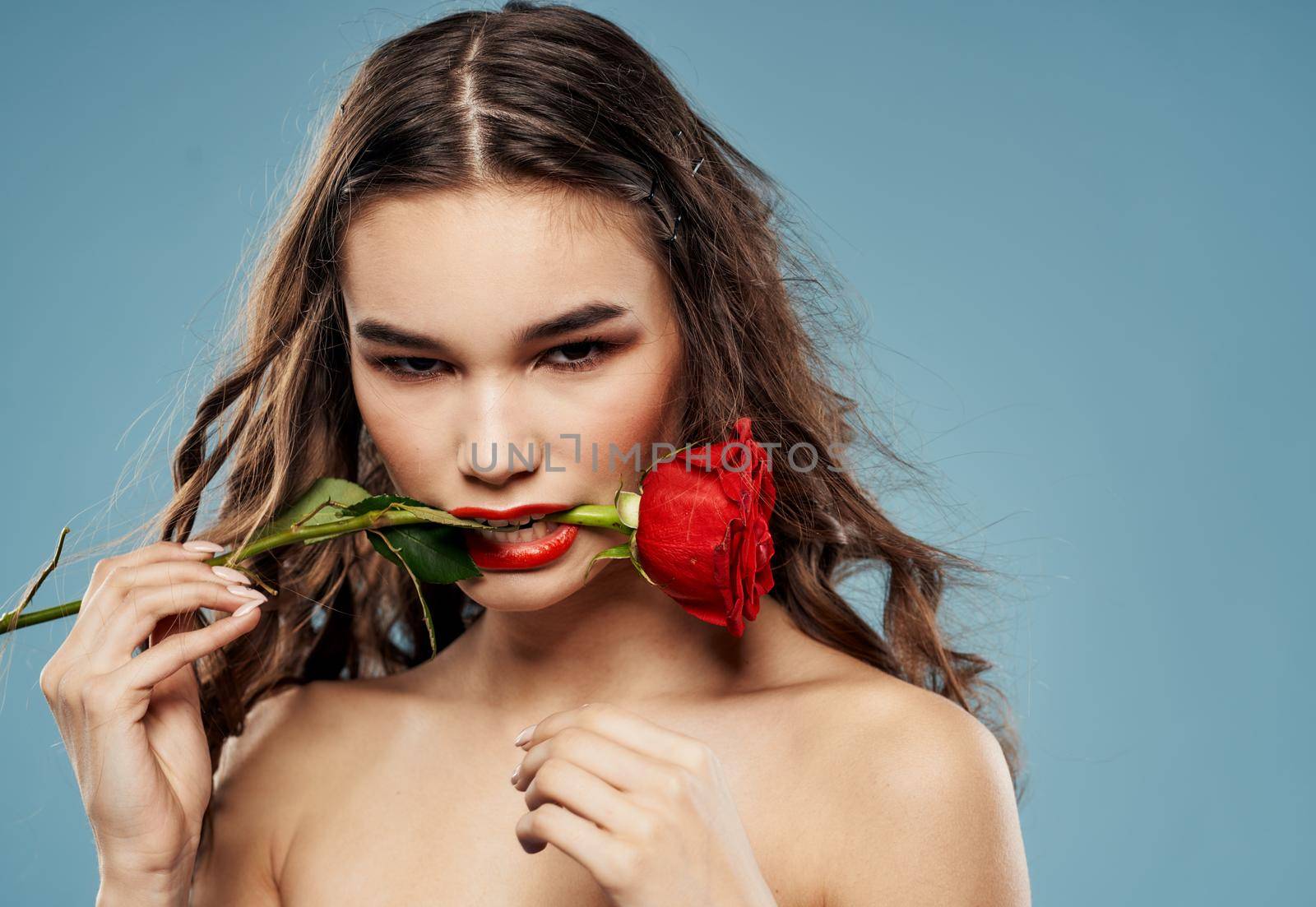 Passionate woman with red rose eye shadow on eyelids blue background cropped view. High quality photo