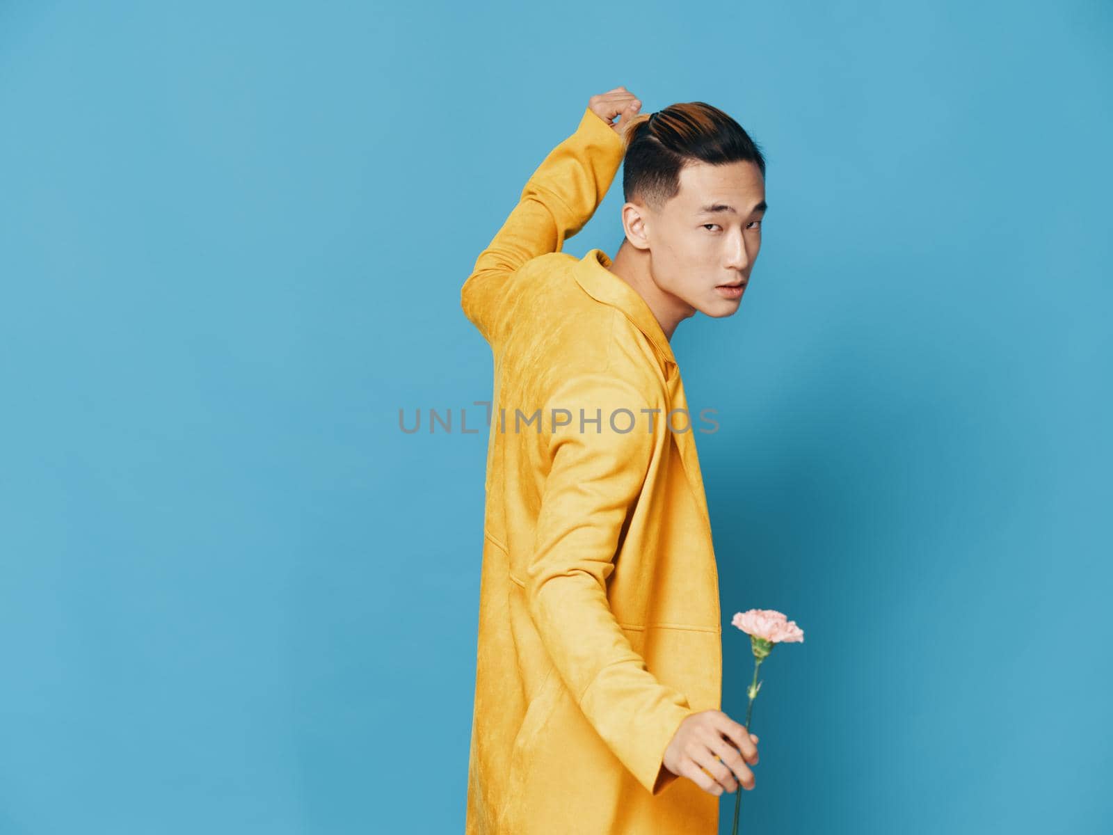 man in yellow coat with flower dancing on blue background. High quality photo