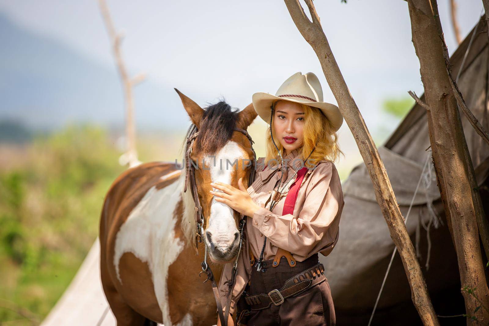 Cowgirl standing by horse at outdoor farm. 