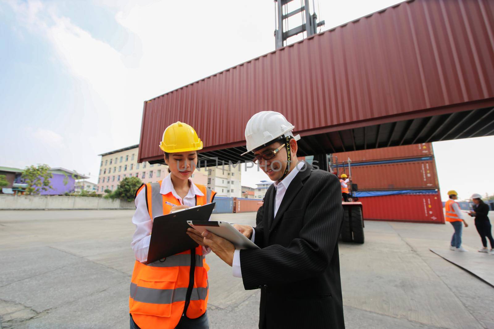 Engineer or supervisor checking and control loading Containers box from Cargo at harbor.Foreman control Industrial Container Cargo freight ship at industry.Transportation and logistic concept.  by chuanchai