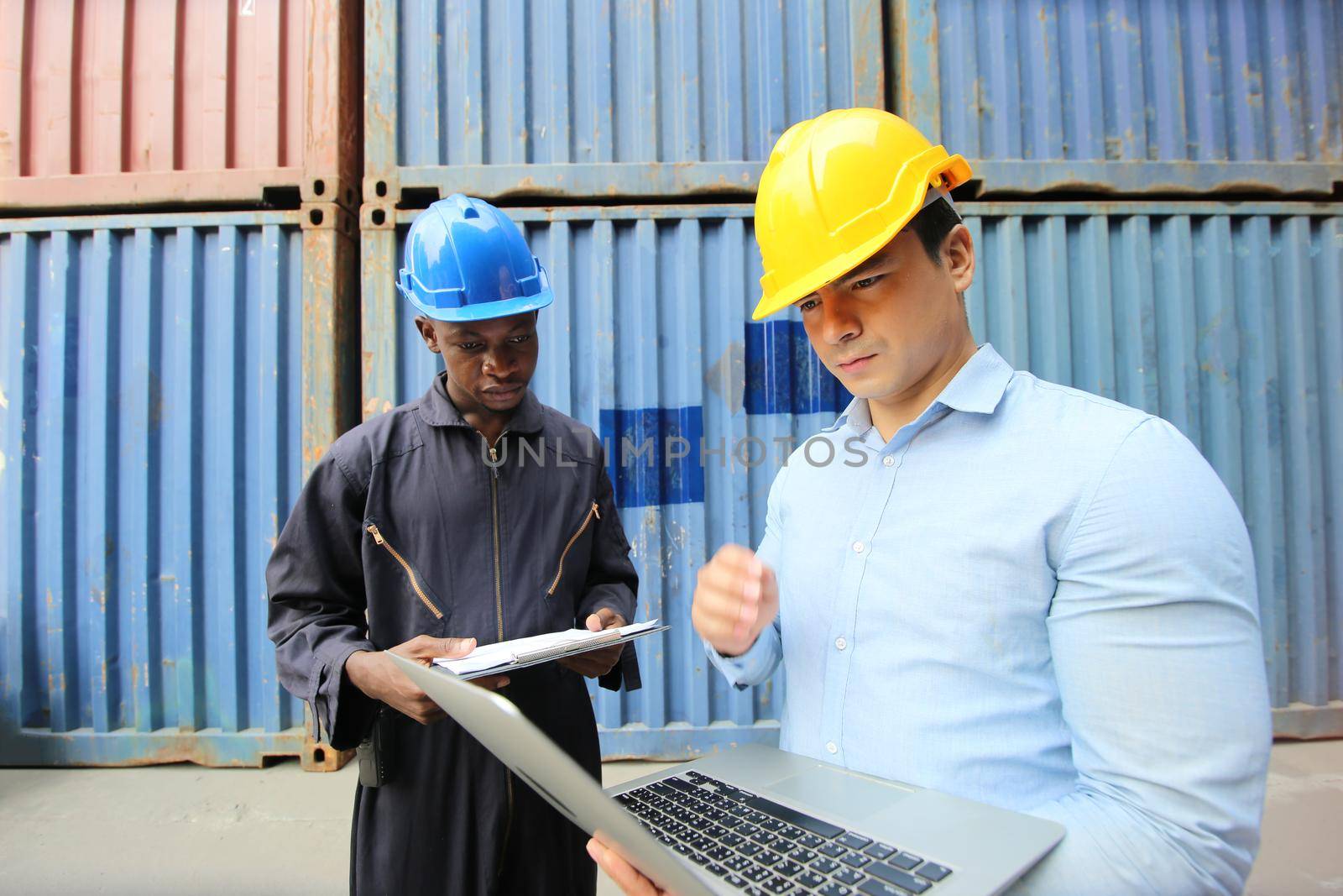 Engineer or supervisor checking and control loading Containers box from Cargo at harbor.Foreman control Industrial Container Cargo freight ship at industry.Transportation and logistic concept. 