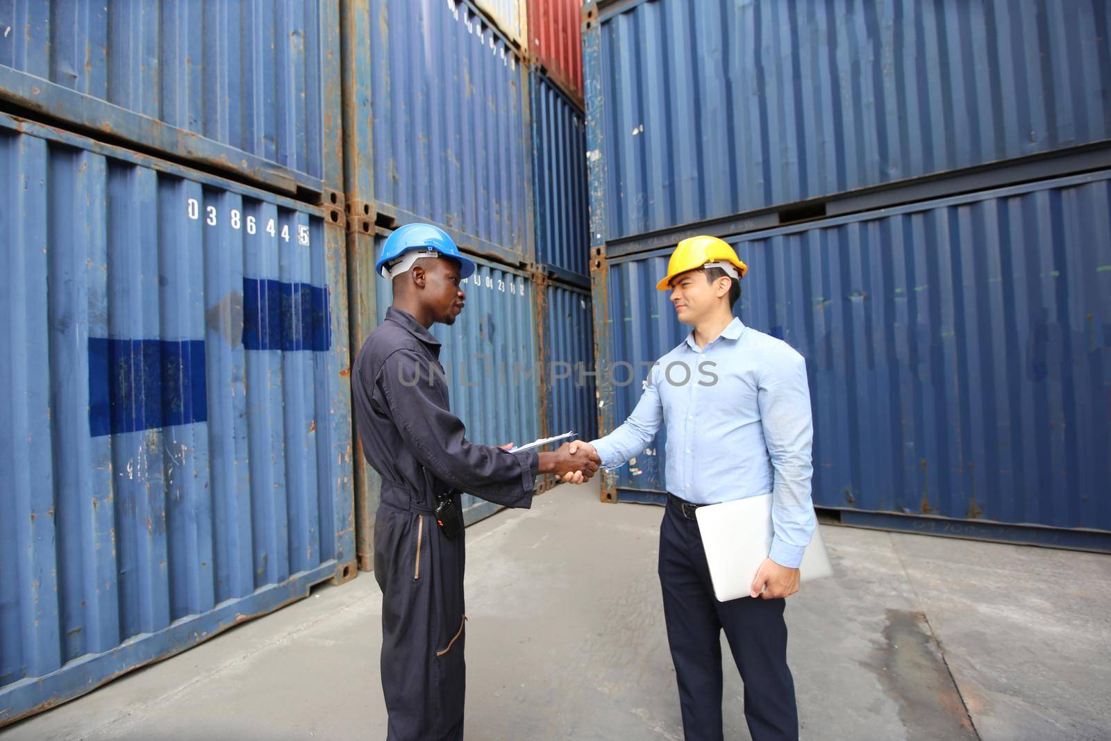 Engineer or supervisor checking and control loading Containers box from Cargo at harbor.Foreman control Industrial Container Cargo freight ship at industry.Transportation and logistic concept. 