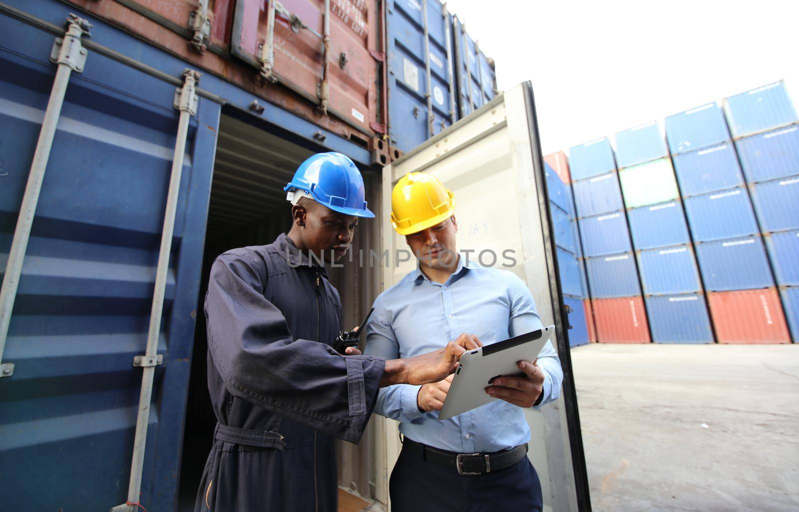 Engineer or supervisor checking and control loading Containers box from Cargo at harbor.Foreman control Industrial Container Cargo freight ship at industry.Transportation and logistic concept. 