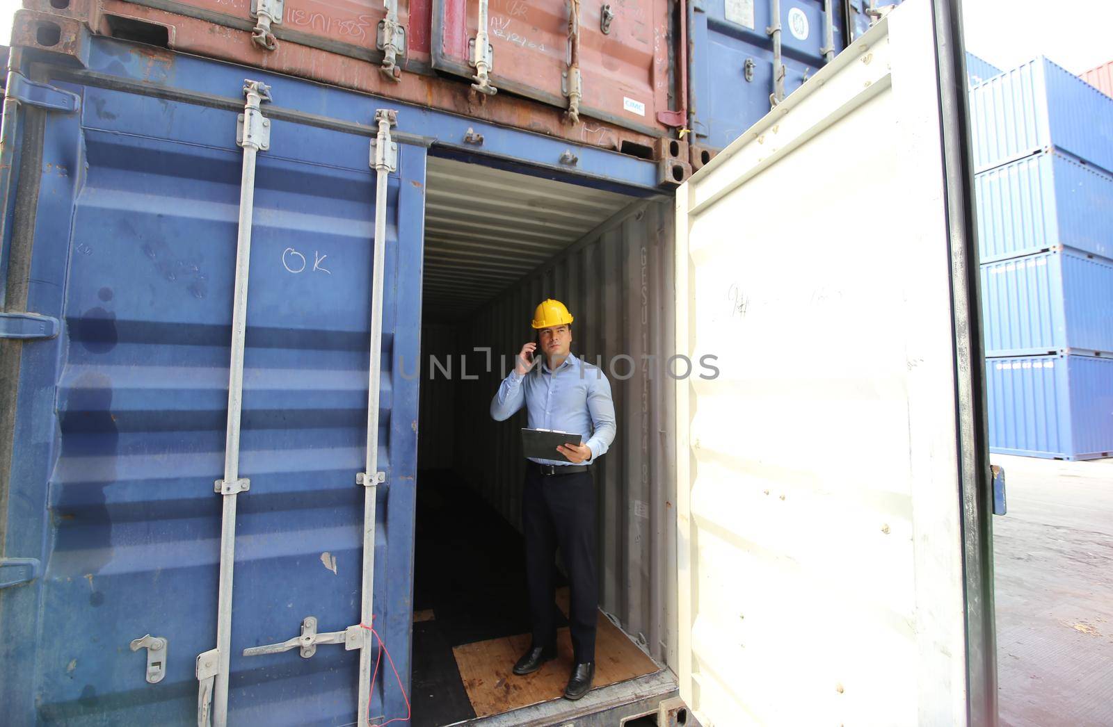 Engineer or supervisor checking and control loading Containers box from Cargo at harbor.Foreman control Industrial Container Cargo freight ship at industry.Transportation and logistic concept. 