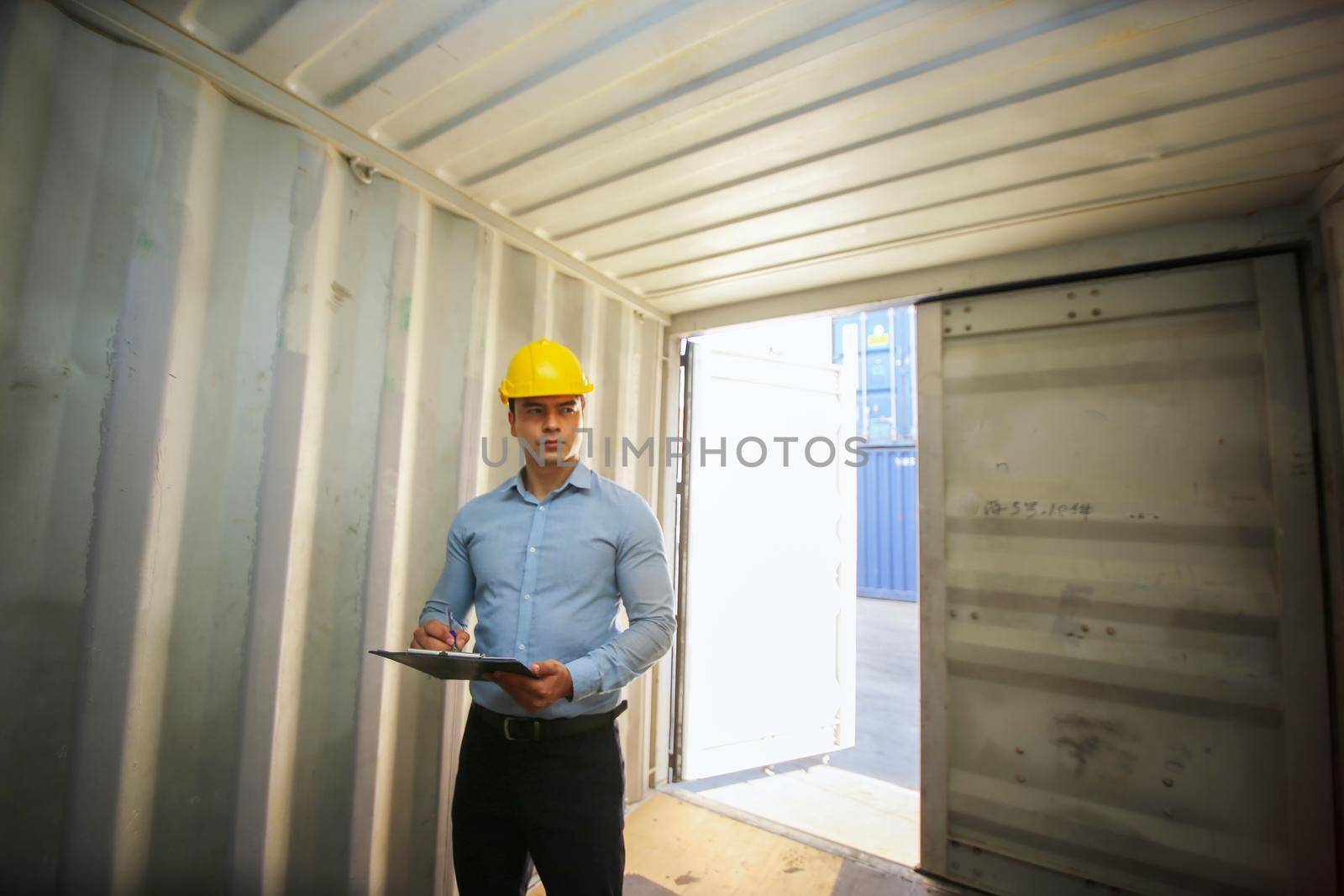 Engineer or supervisor checking and control loading Containers box from Cargo at harbor.Foreman control Industrial Container Cargo freight ship at industry.Transportation and logistic concept. 
