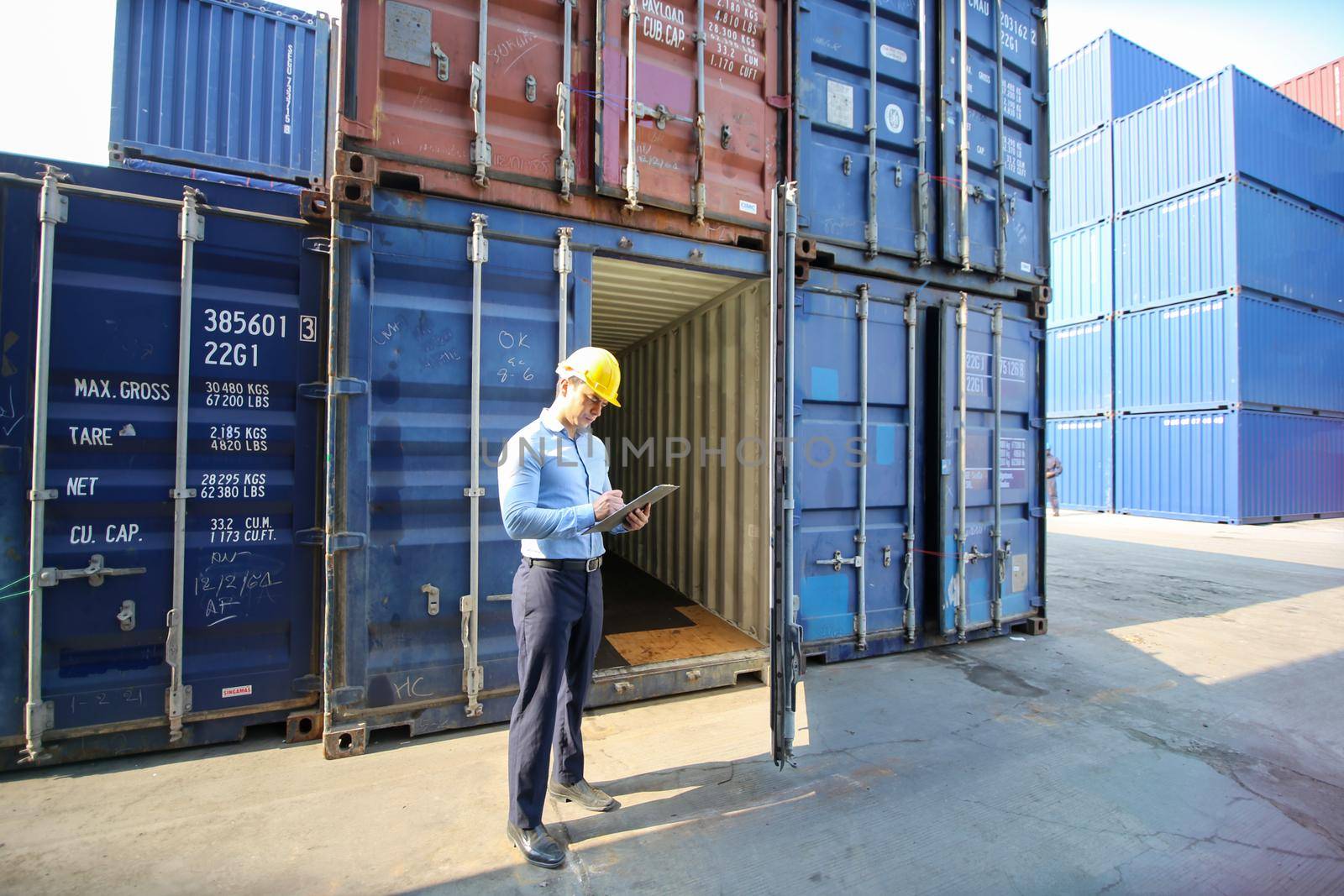 Engineer or supervisor checking and control loading Containers box from Cargo at harbor.Foreman control Industrial Container Cargo freight ship at industry.Transportation and logistic concept. 