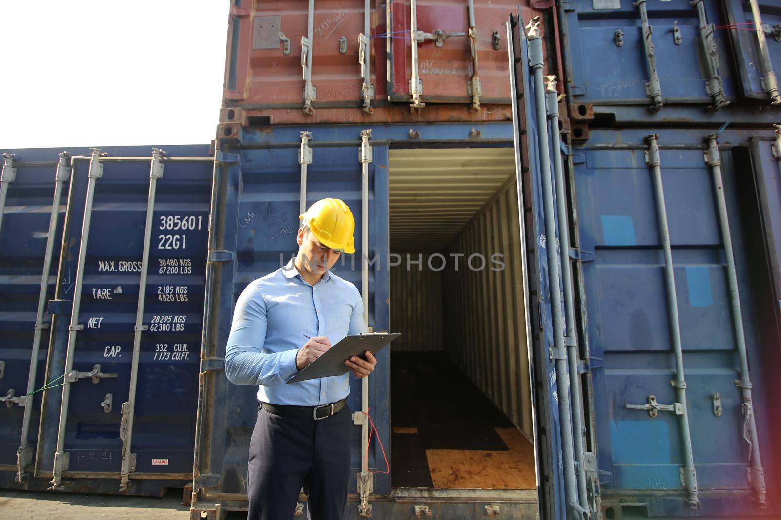 Engineer or supervisor checking and control loading Containers box from Cargo at harbor.Foreman control Industrial Container Cargo freight ship at industry.Transportation and logistic concept. 