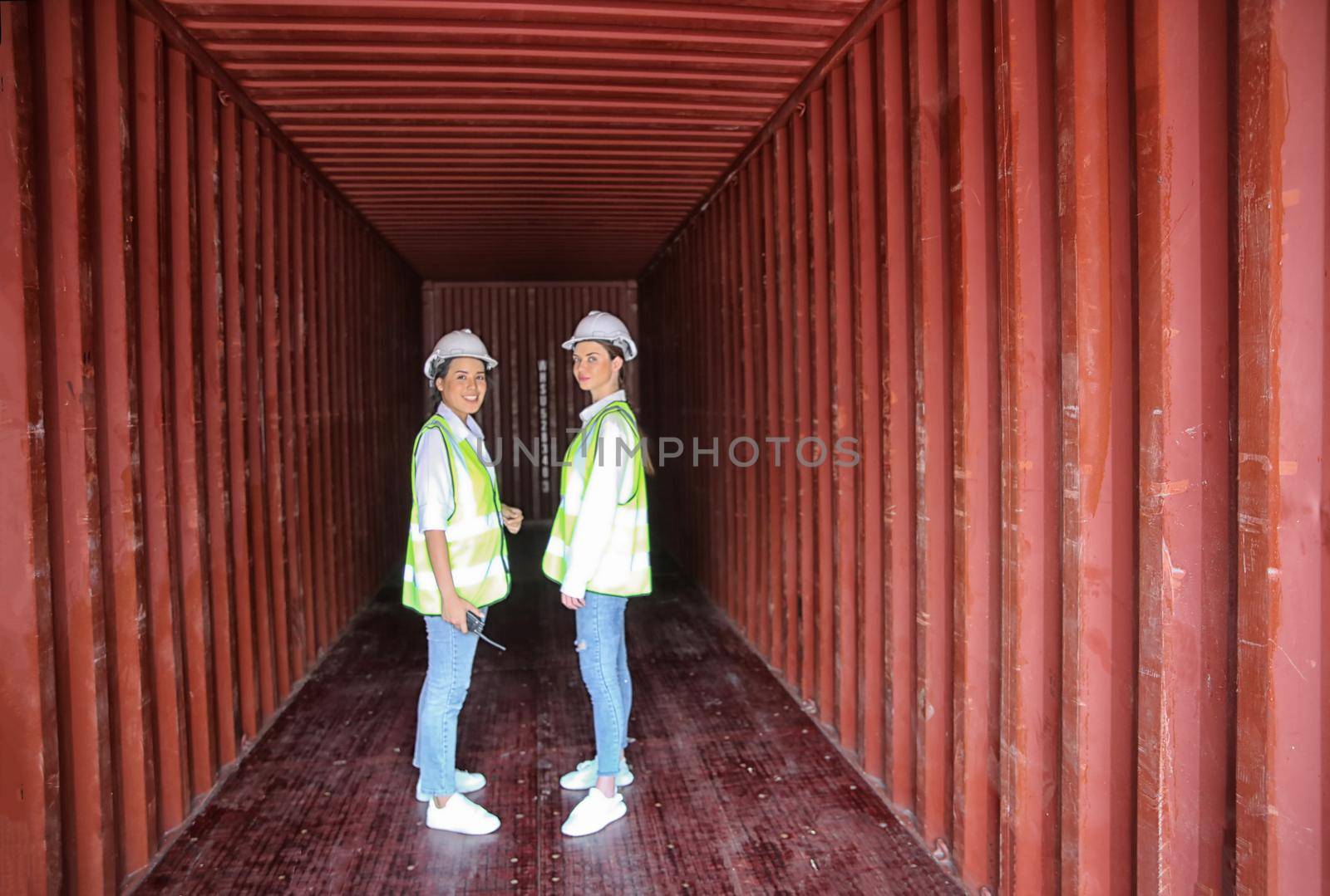 Female workers smiling and standing inside contrainer.