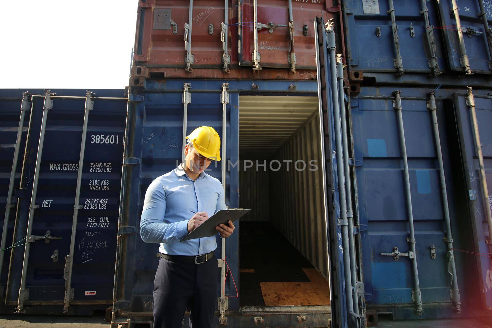 Foreman control loading Containers box from Cargo freight ship for import export.