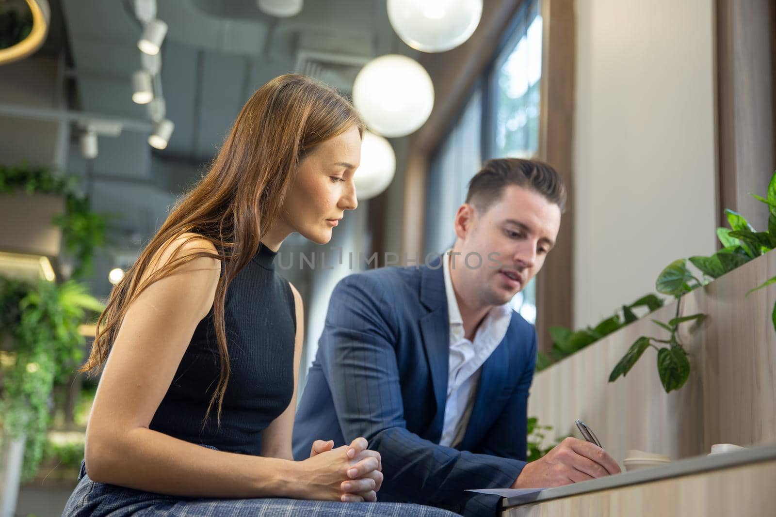 Close-up image of two attractive young people having a business meeting in a modern cafe. by chuanchai