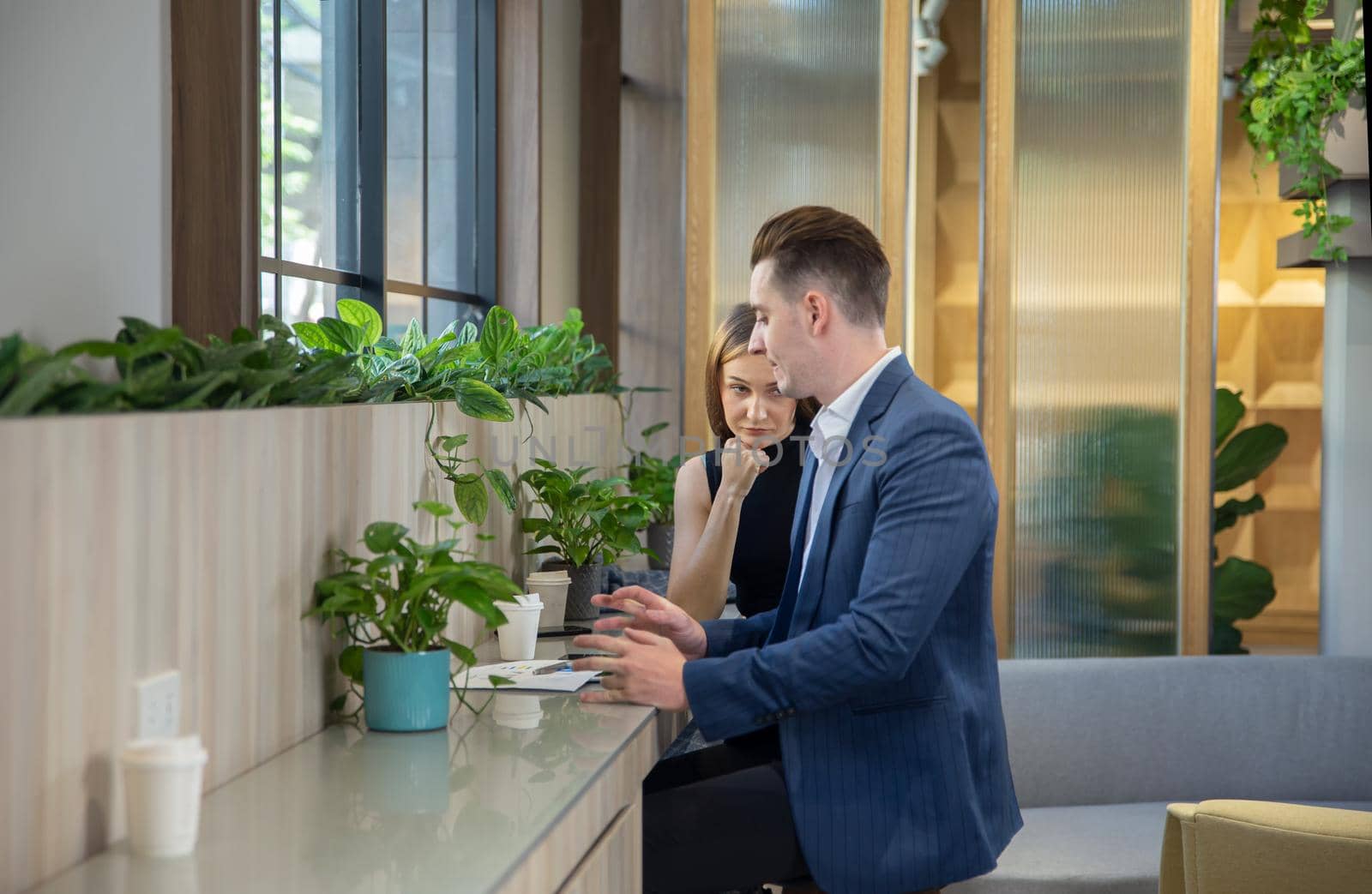 Close-up image of two attractive young people having a business meeting in a modern cafe.