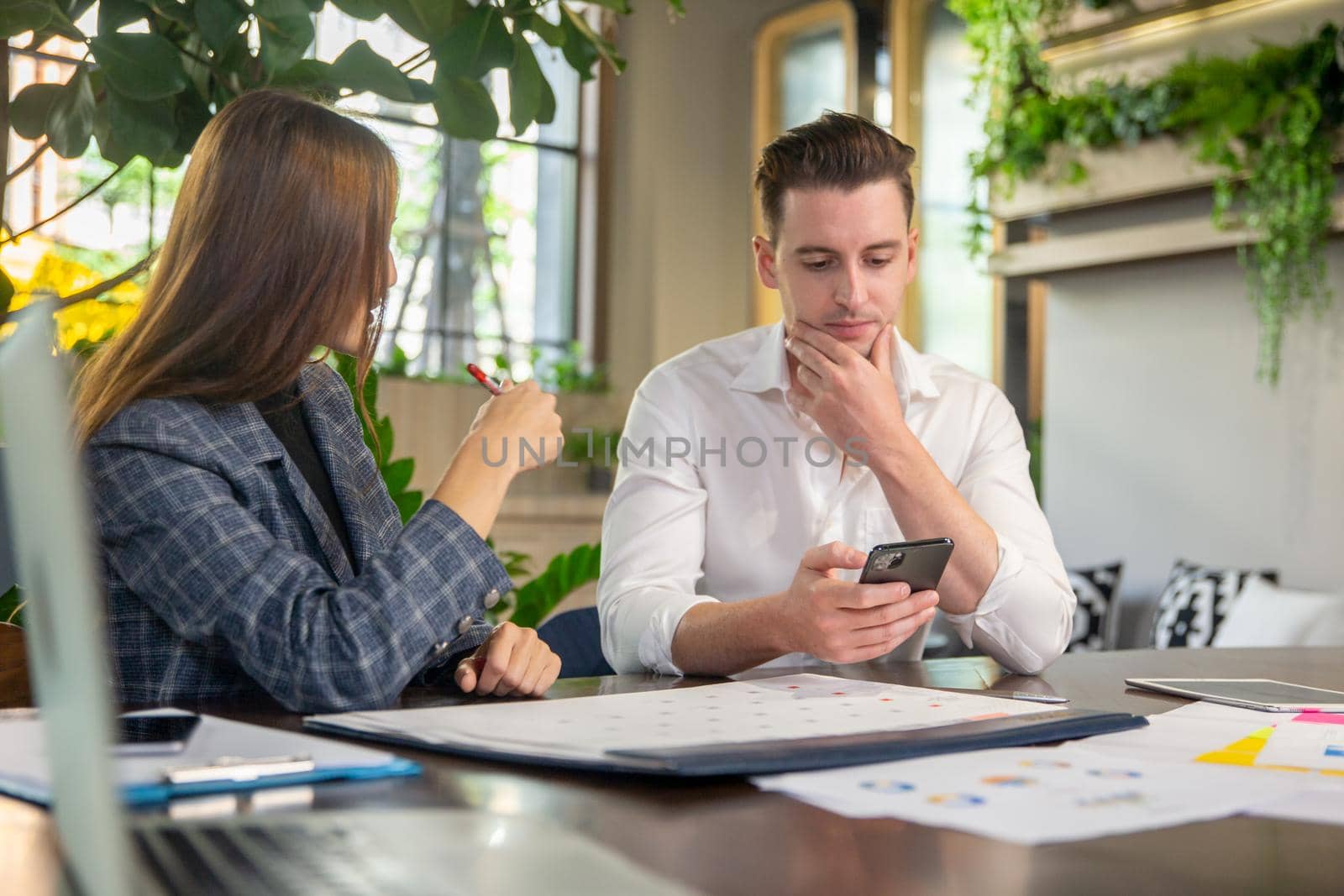 Close-up image of two attractive young people having a business meeting in a modern cafe.