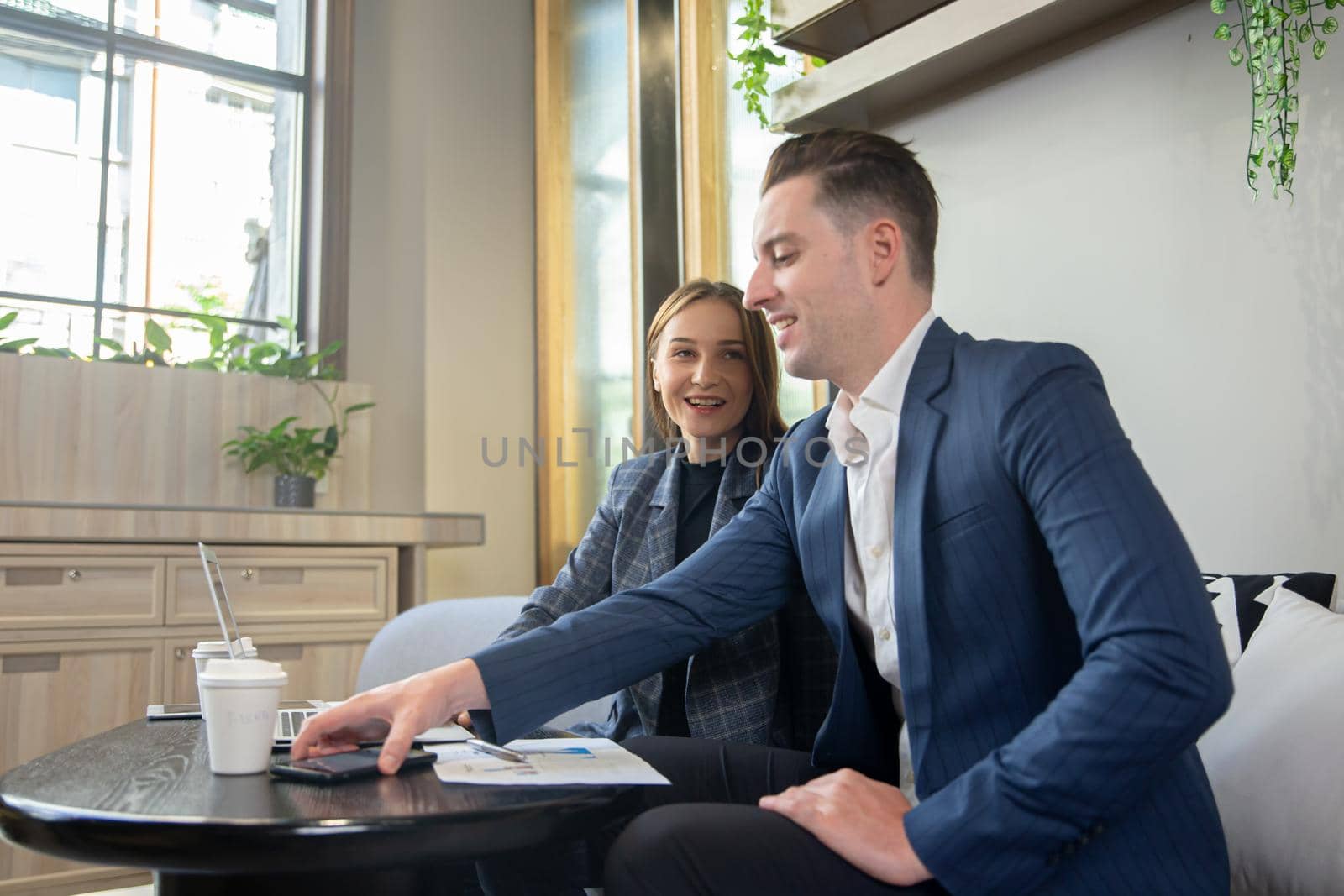 Close-up image of two attractive young people having a business meeting in a modern cafe.