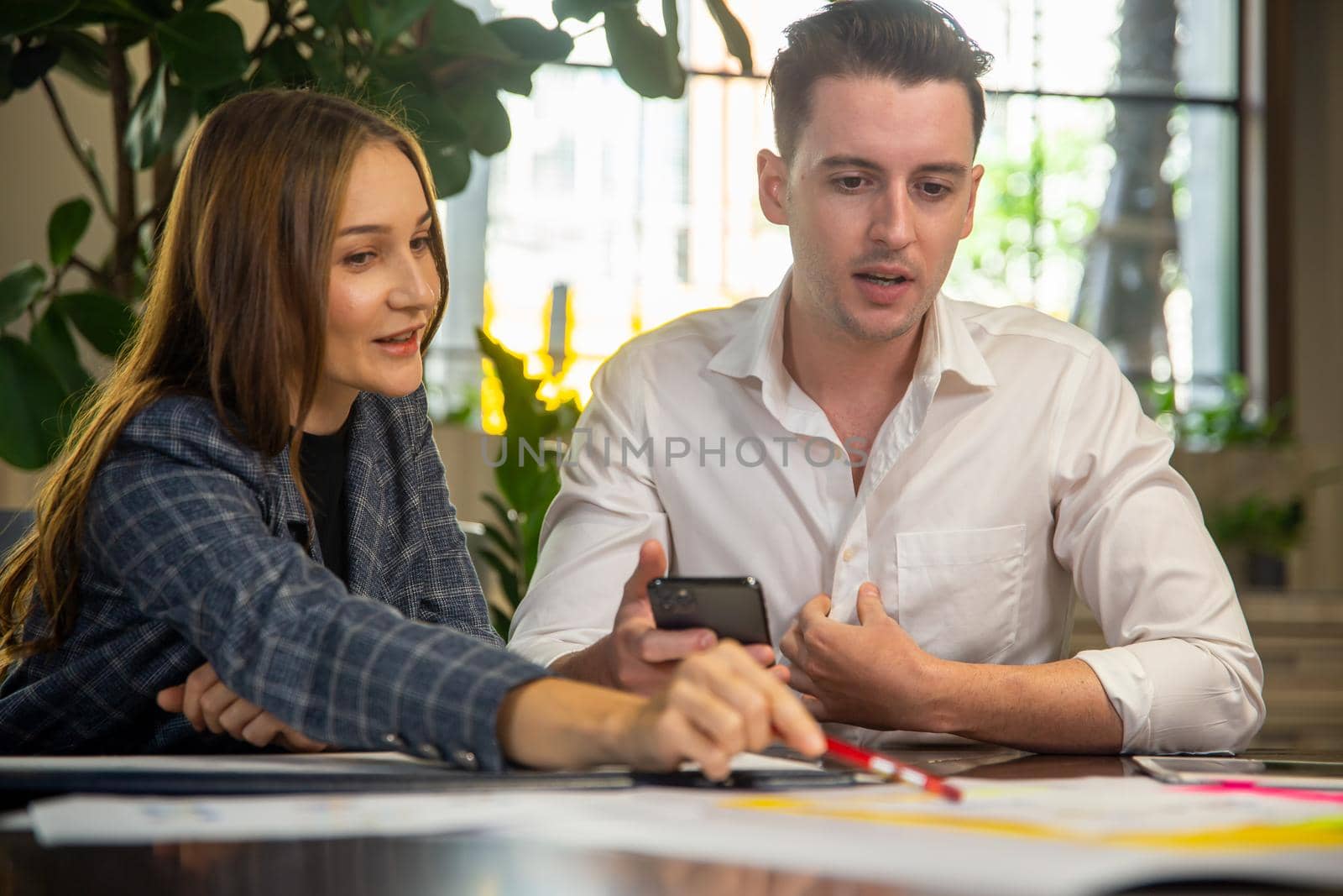 Close-up image of two attractive young people having a business meeting in a modern cafe.