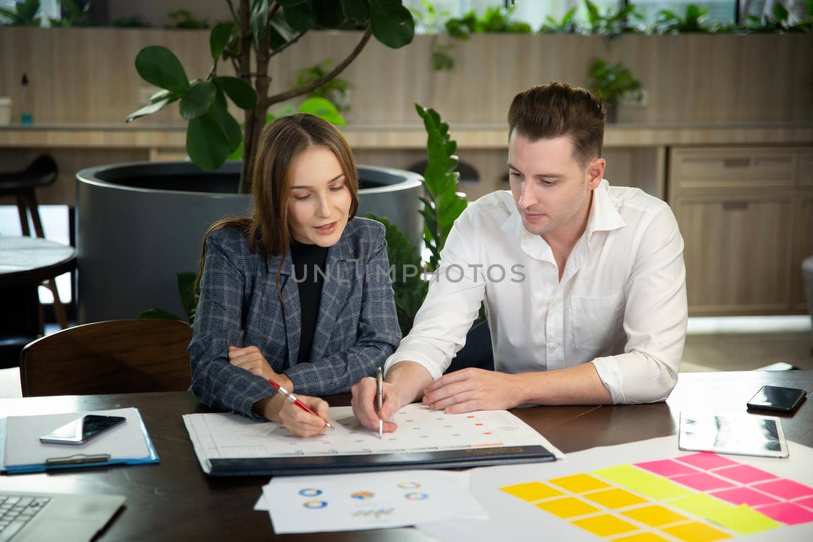 Close-up image of two attractive young people having a business meeting in a modern cafe.