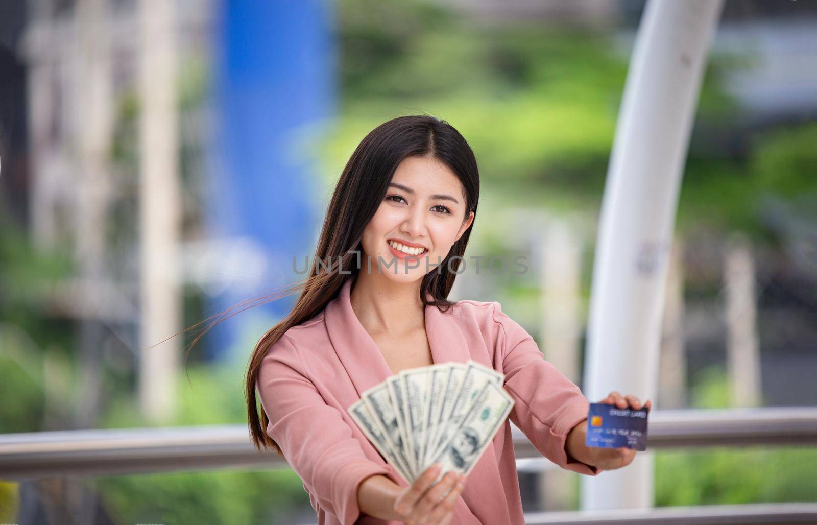 young asian women holding money and credit card at outdoor.