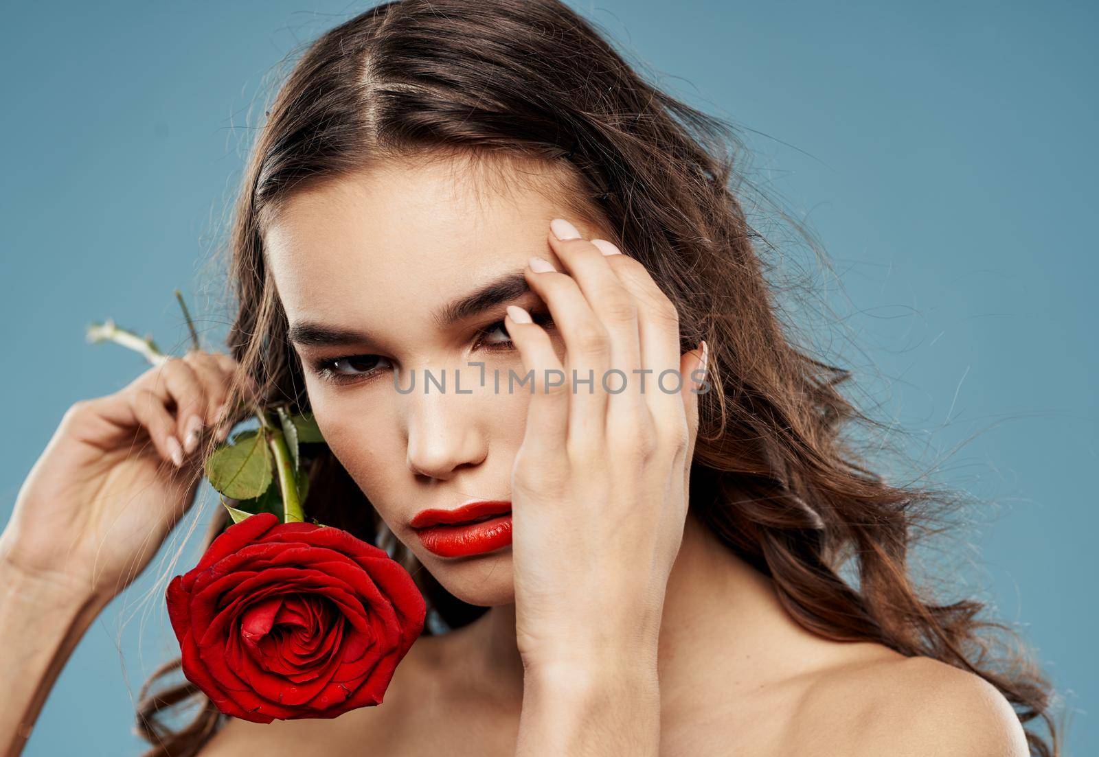 Passionate woman with red rose eye shadow on eyelids blue background cropped view. High quality photo