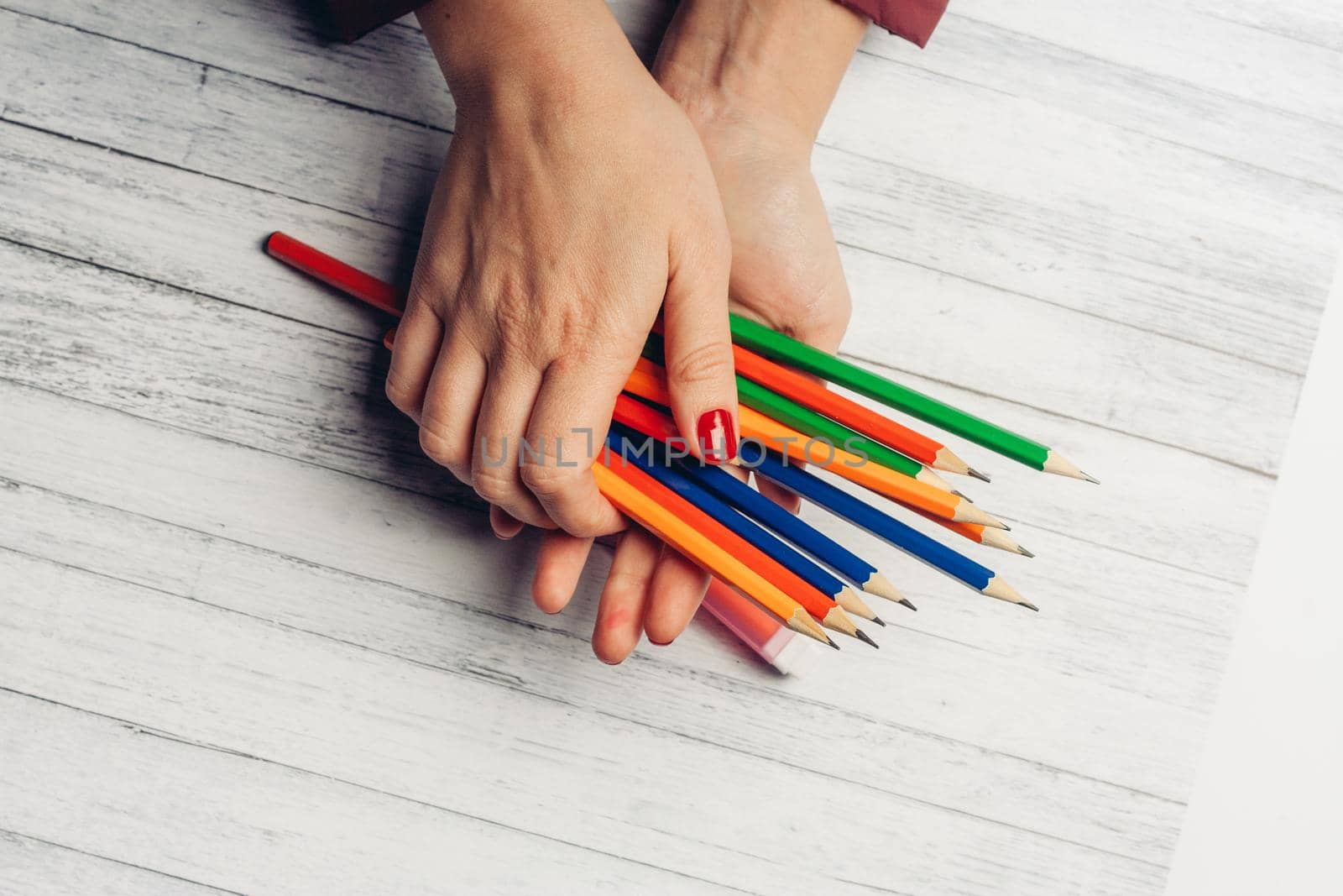 colored pencils in female hands on a wooden background close up. High quality photo