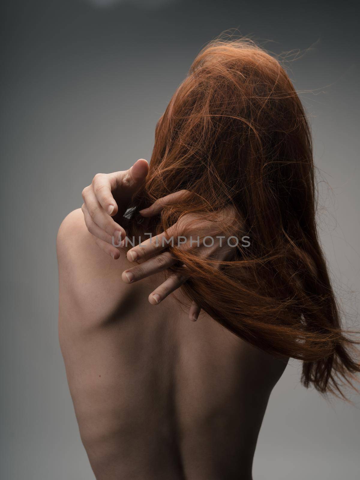 Back view of sexy red-haired woman naked back touching with hands by SHOTPRIME