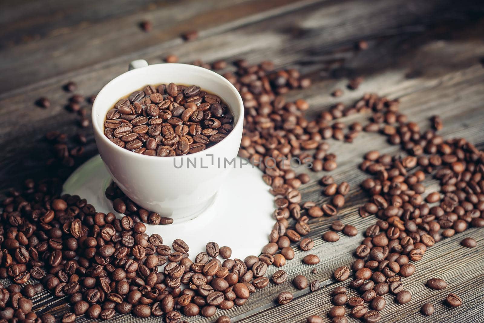 coffee beans on a wooden background and a cup on a saucer close-up macro photography. High quality photo