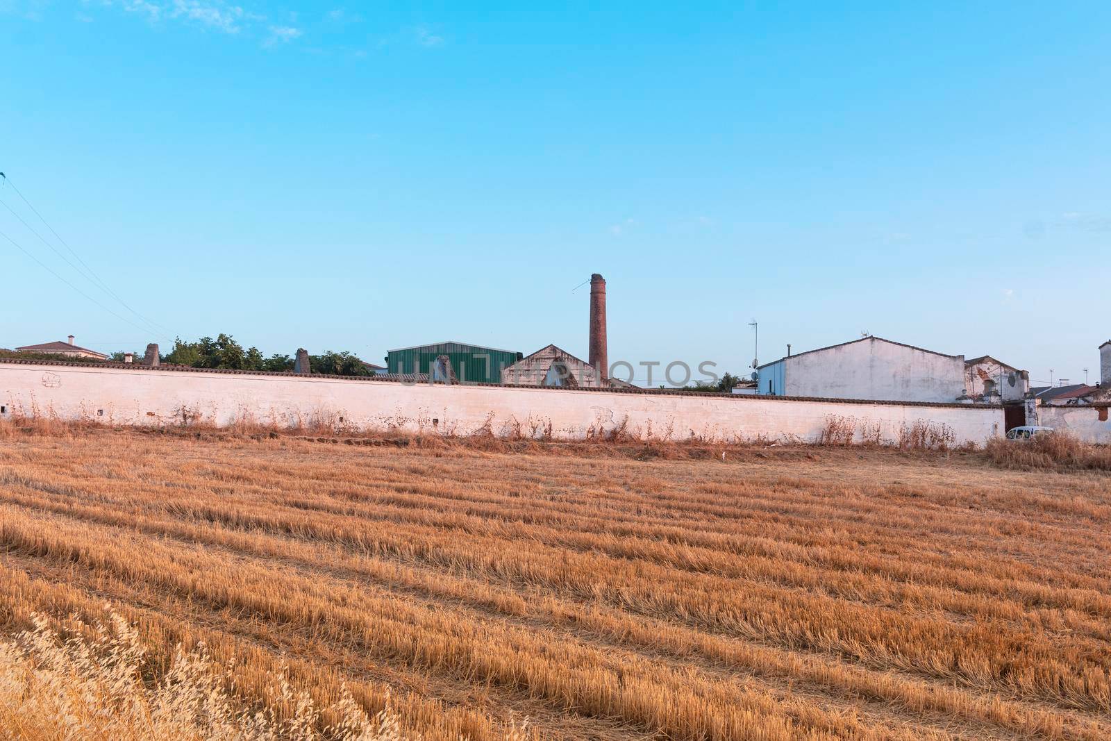 Freshly picked dry cereal field with factory in the background, in southern Andalusia Spain.