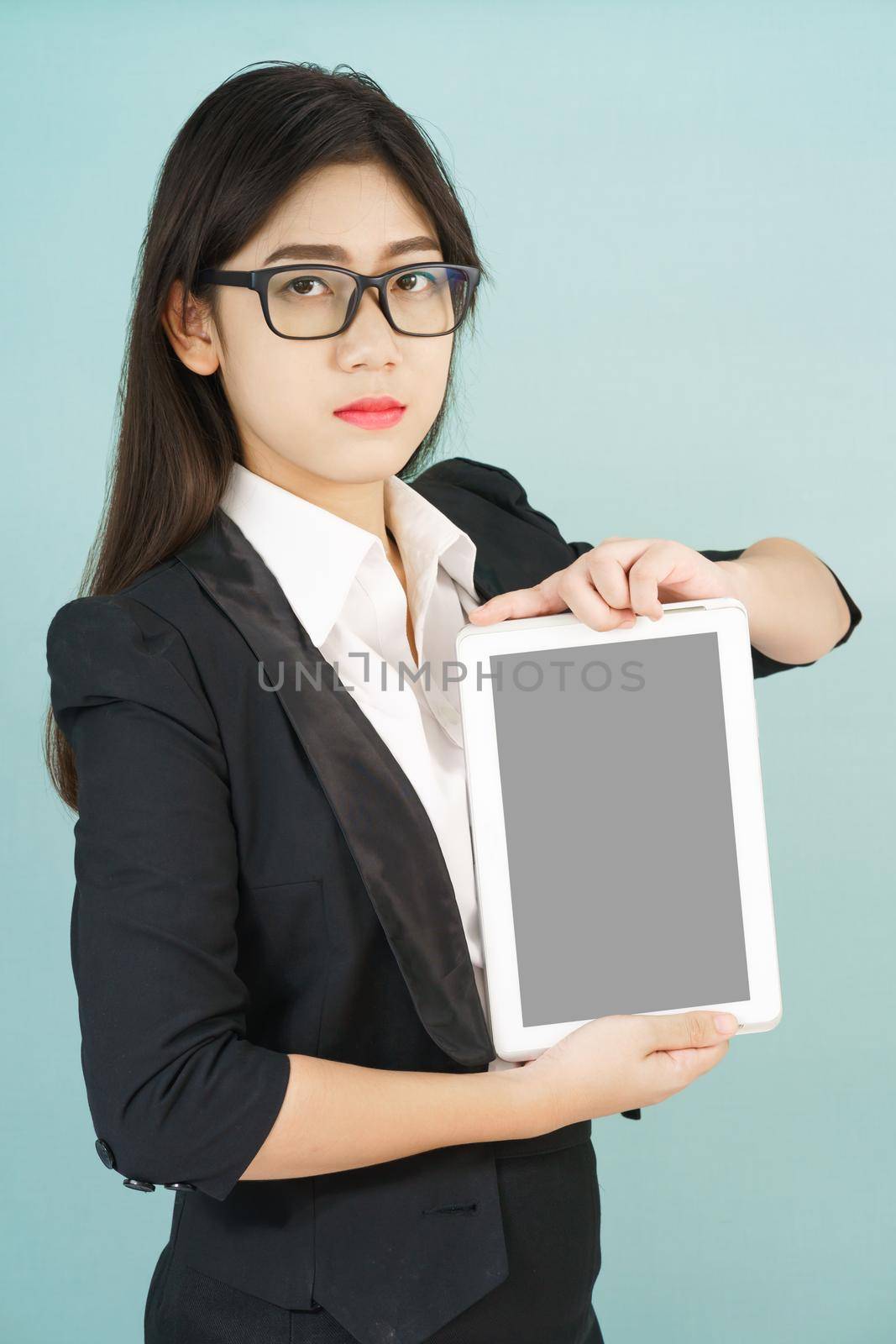 Young asian women in suit holding her digital tablet standing against green background