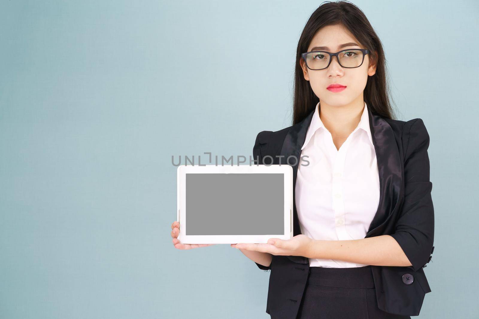 Young asian women in suit holding her digital tablet standing against green background