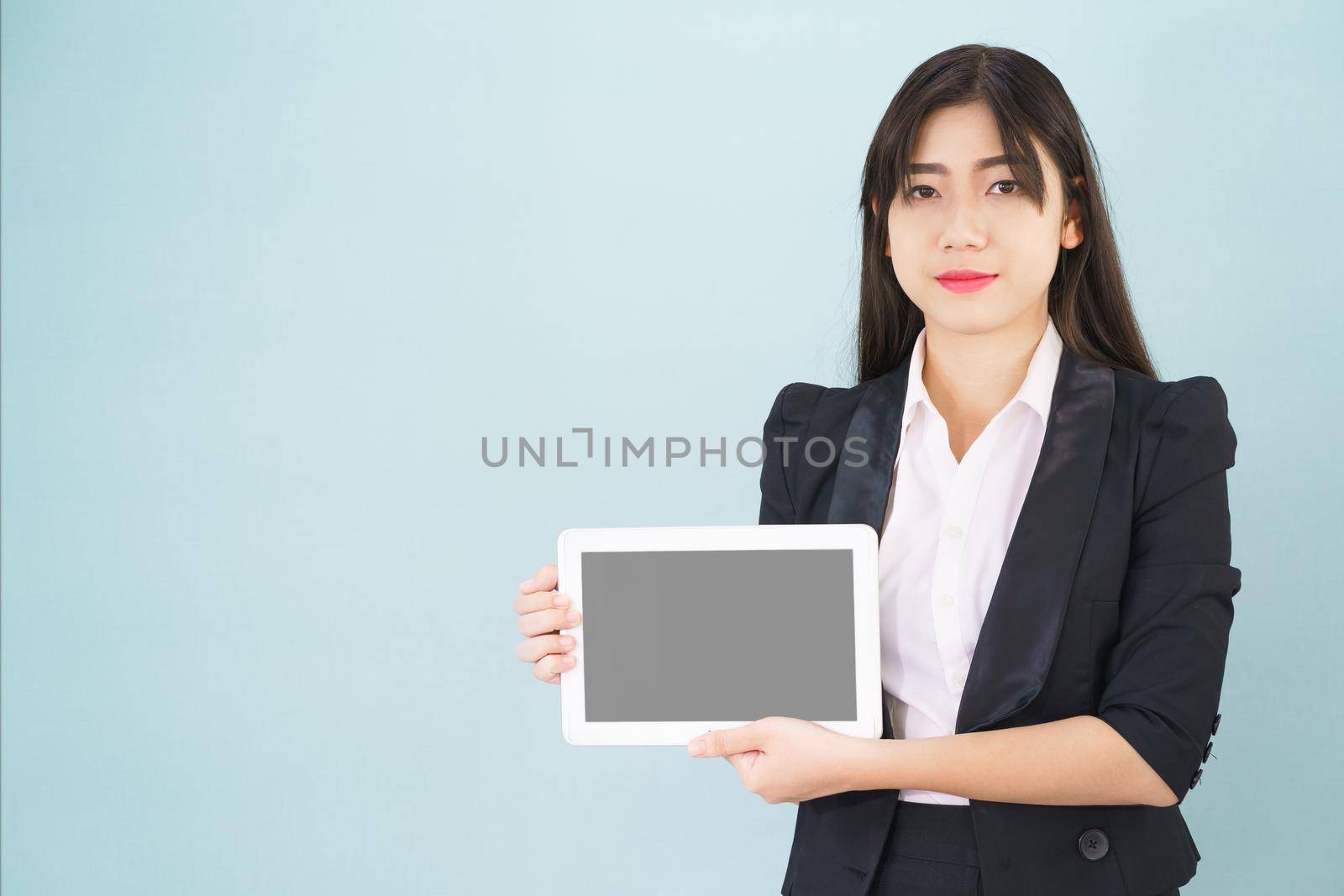 Young women in suit holding her digital tablet standing against blue background