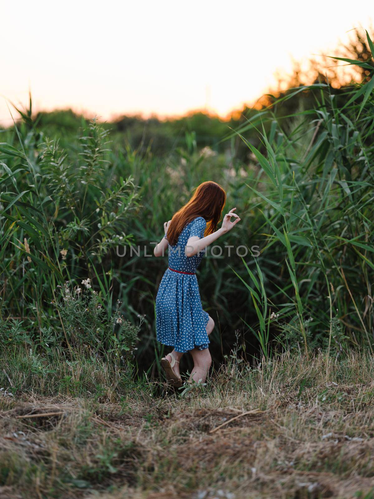 Woman in blue dress near green bushes in the garden in nature by SHOTPRIME