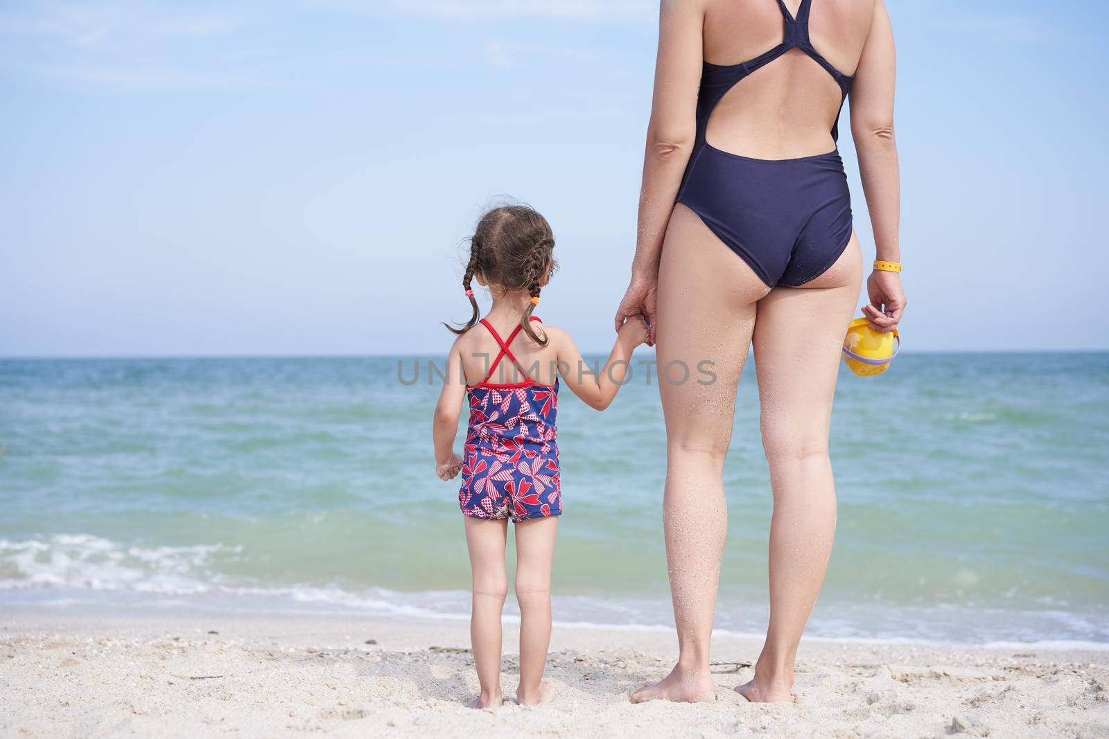 Mother daughter beach together rear view Unrecognizable caucasian woman little girl swimwear standing seaside back Family with one child. Family Vacation Summertime