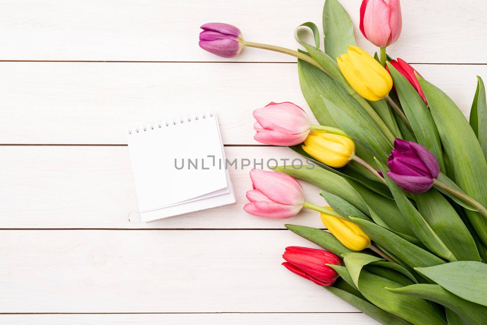 Top view of blank calendar with colorful tulips on white background. Mock up design