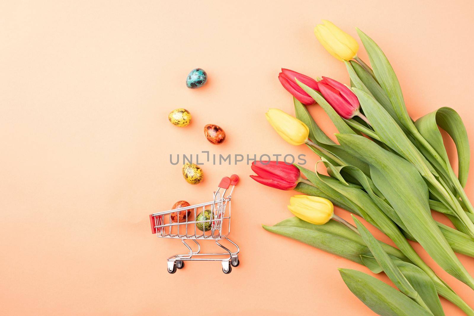 Shopping cart with colorful bouquet of tulips on orange background by Desperada