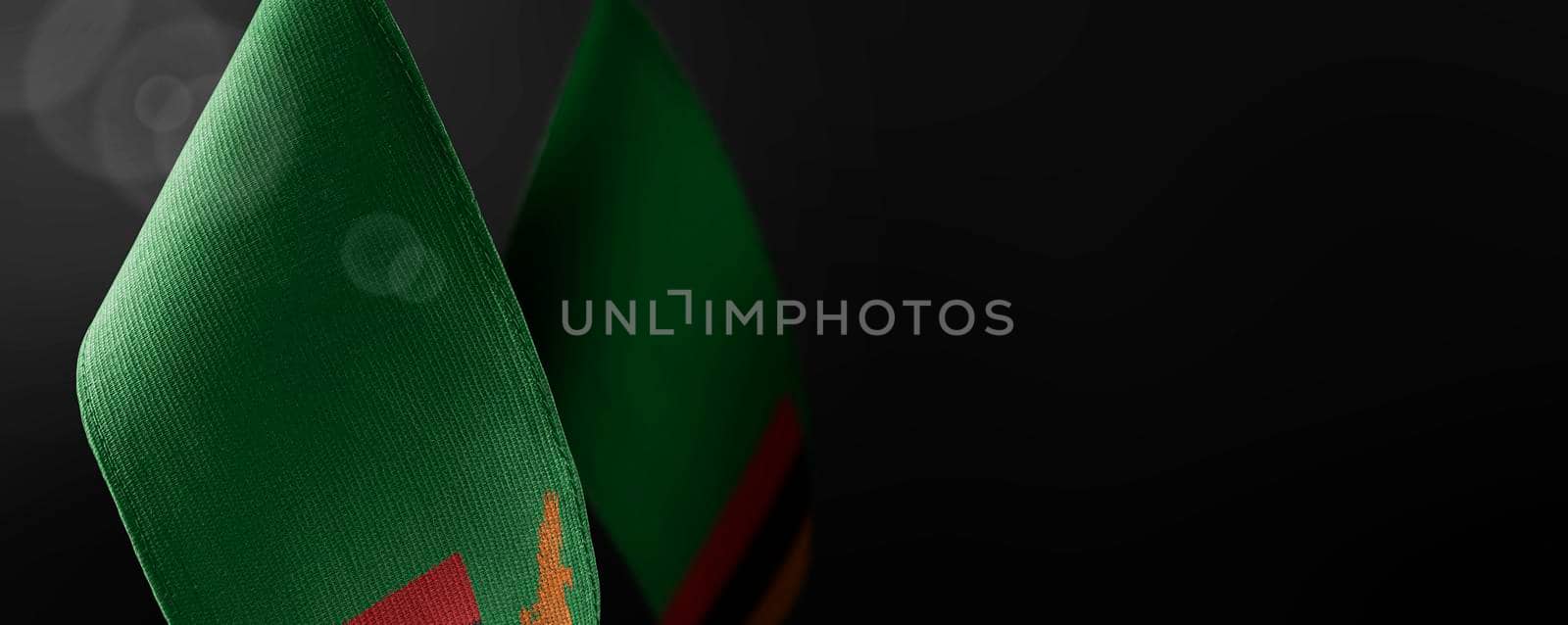 Small national flags of the Zambia on a dark background.