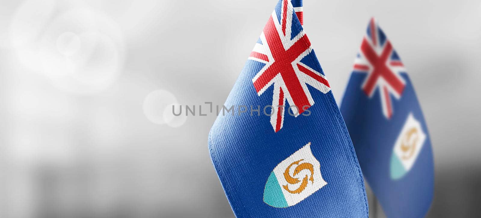 Small national flags of the Anguilla on a light blurry background.